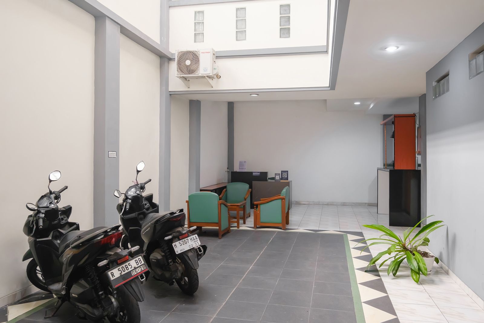 A clean, modern indoor space with two motorcycles parked, a reception desk, and a potted plant.