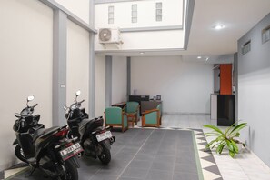 A clean, modern indoor space with two motorcycles parked, a reception desk, and a potted plant. - INNCA Singa Utara, Semarang (Semarang)