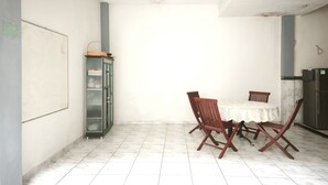 A room with a tiled floor, a table with chairs, a refrigerator, and a cabinet. - INNCA Singa Utara, Semarang (Semarang)