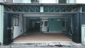A covered entrance to a building with a tiled floor and metal gates. - INNCA Singa Utara, Semarang (Semarang)