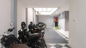 Un pasillo con varias motocicletas estacionadas, un ventilador de techo y una planta.