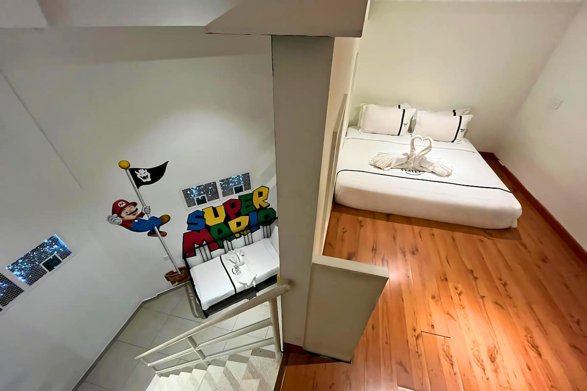 A room with a bed, a small table, and a wall decoration featuring a character holding a flag.