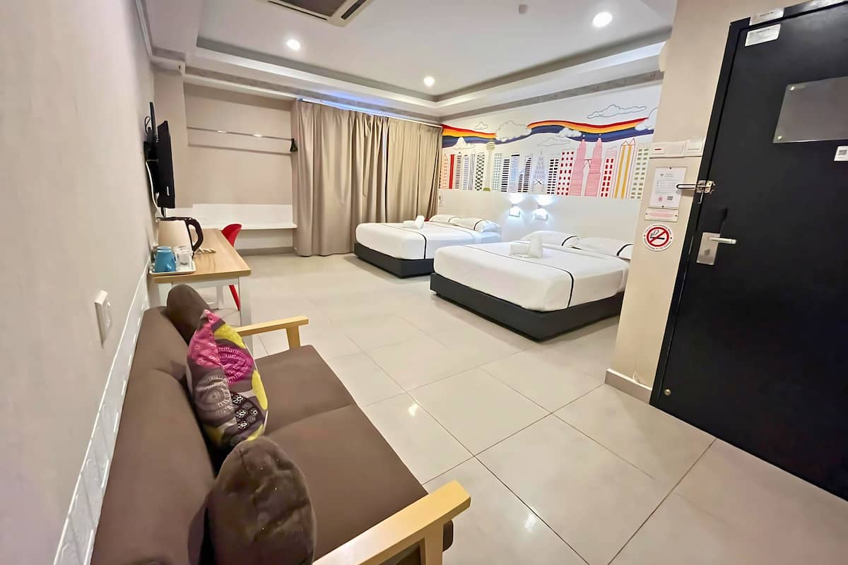 A modern hotel room with a sofa, two beds, a desk with a coffee maker, and a wall with a cityscape mural.