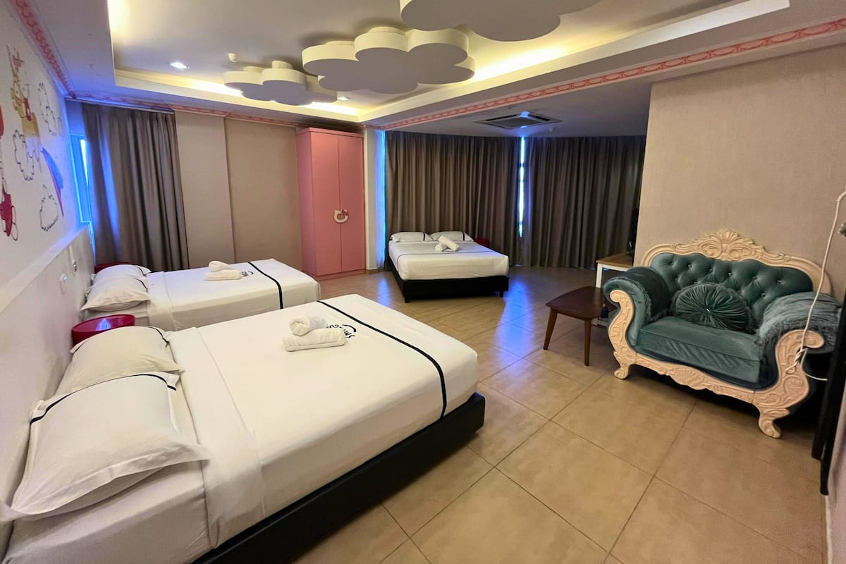 A hotel room with two single beds, a sofa, a desk, and a wardrobe.
