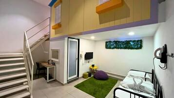A compact, multi-level room with a staircase, a small desk, a green rug, and a bed with white bedding.