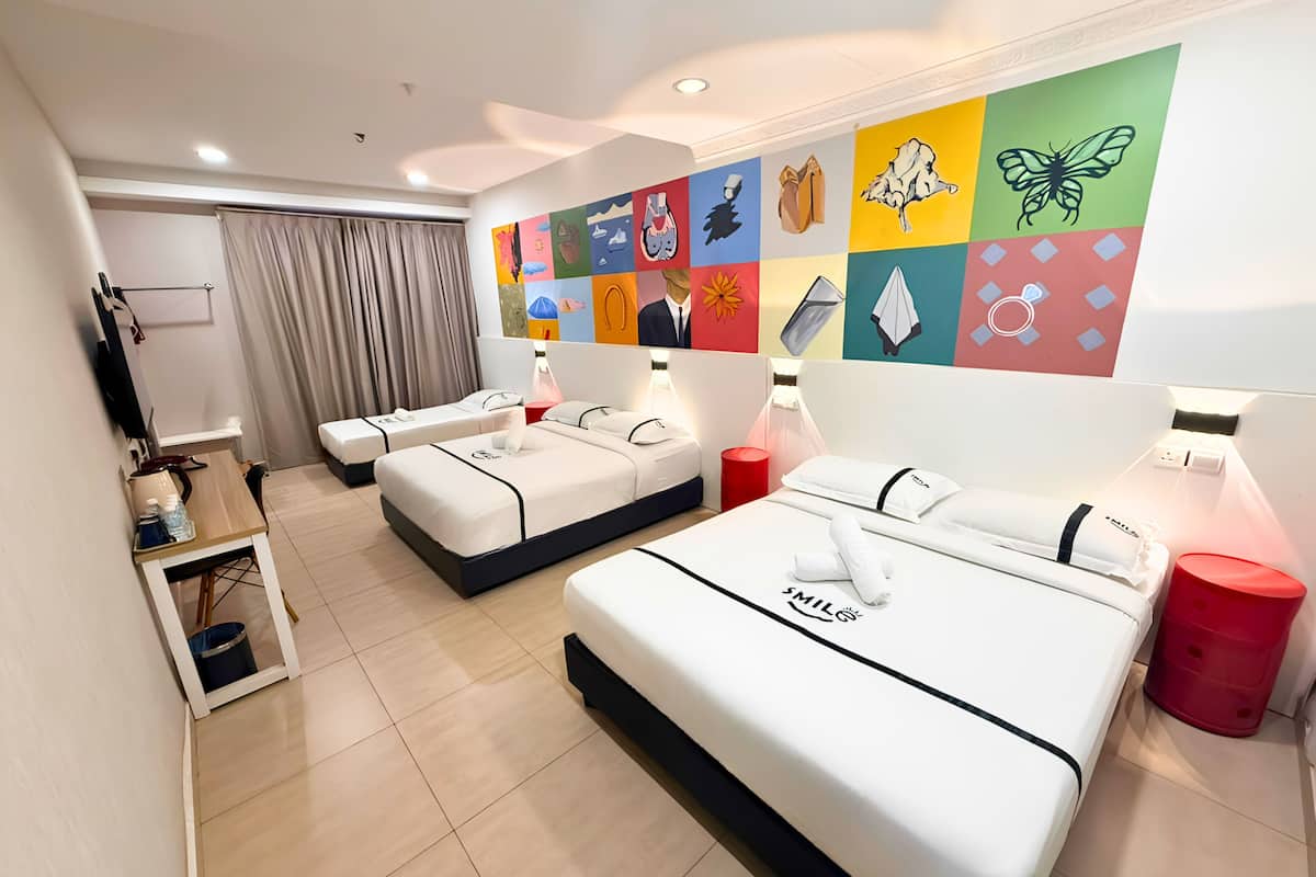 A hotel room with two beds, a desk, a TV, and a colorful wall mural.