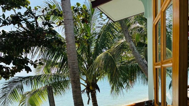 A wooden deck with a view of the beach and palm trees. - Lamai Beachnest Bunaglows (Koh Samui)