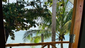 A wooden door leading to a balcony with a view of a beach and palm trees. - Lamai Beachnest Bunaglows (Koh Samui)