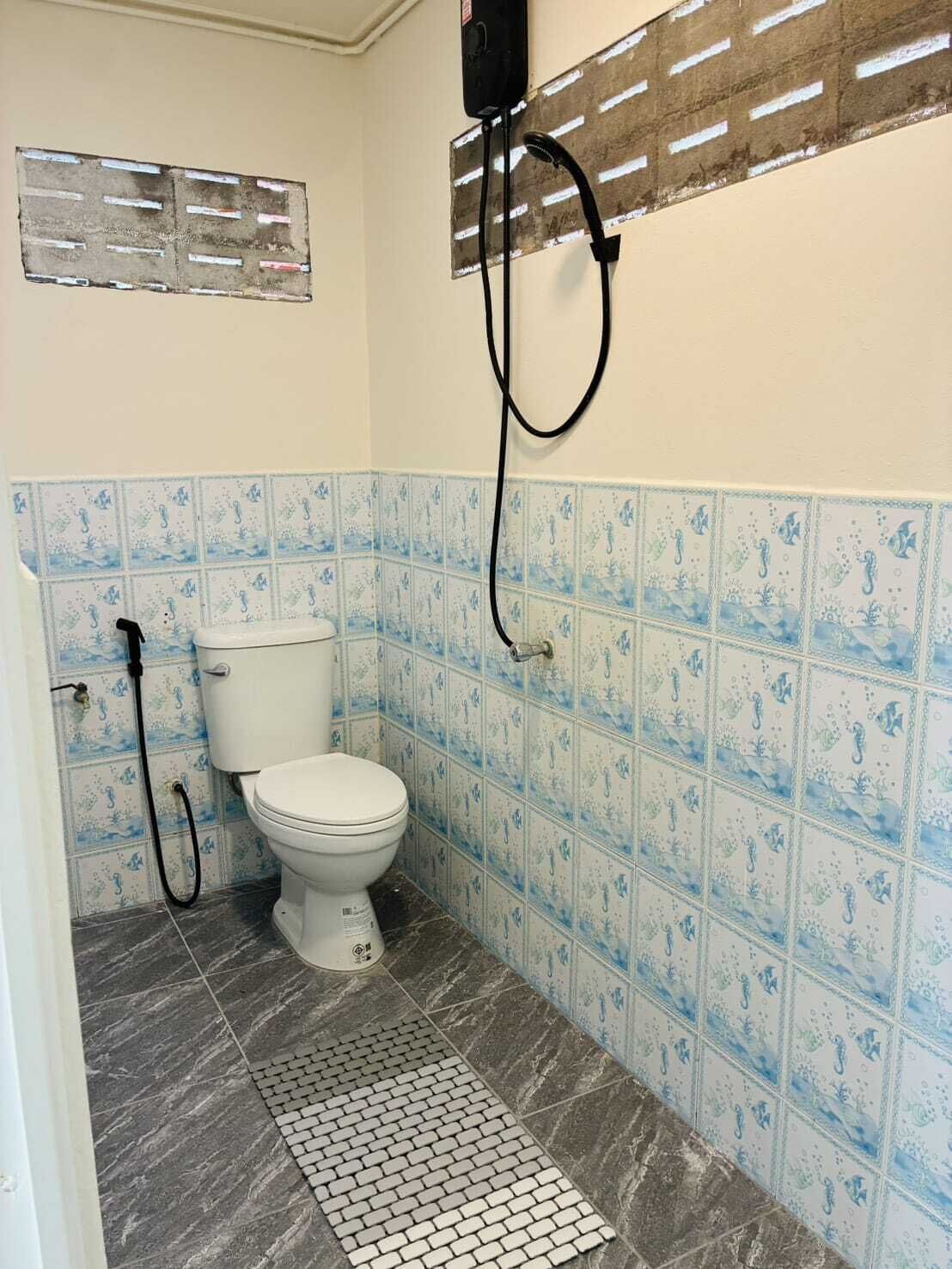 Un baño pequeño con inodoro, ducha y paredes de azulejos.