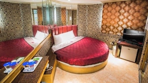 Une chambre d’hôtel avec deux lits, une télévision, un minibar et un miroir.