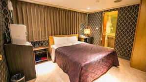 Une chambre d’hôtel avec un lit, un bureau avec un ordinateur, une lampe et un miroir.