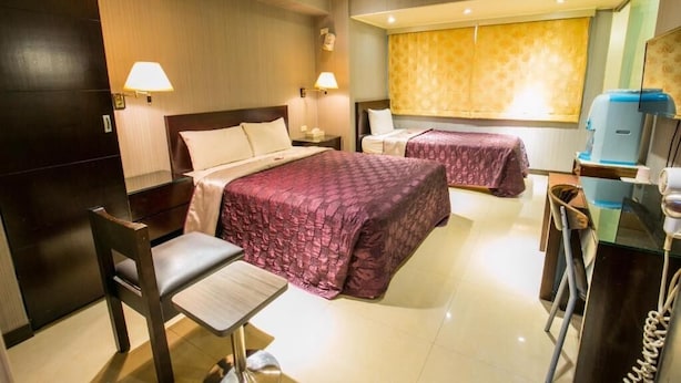 Une chambre d’hôtel avec deux lits, un bureau, une chaise, une table de chevet et un distributeur d’eau.