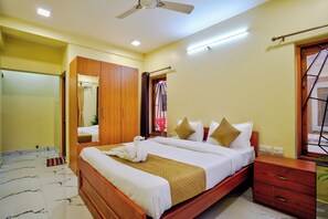 A hotel room with a bed, wooden wardrobe, and a ceiling fan.
