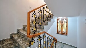 Un escalier avec des marches en marbre et des rampes en fer forgé, peintes en noir et en jaune.