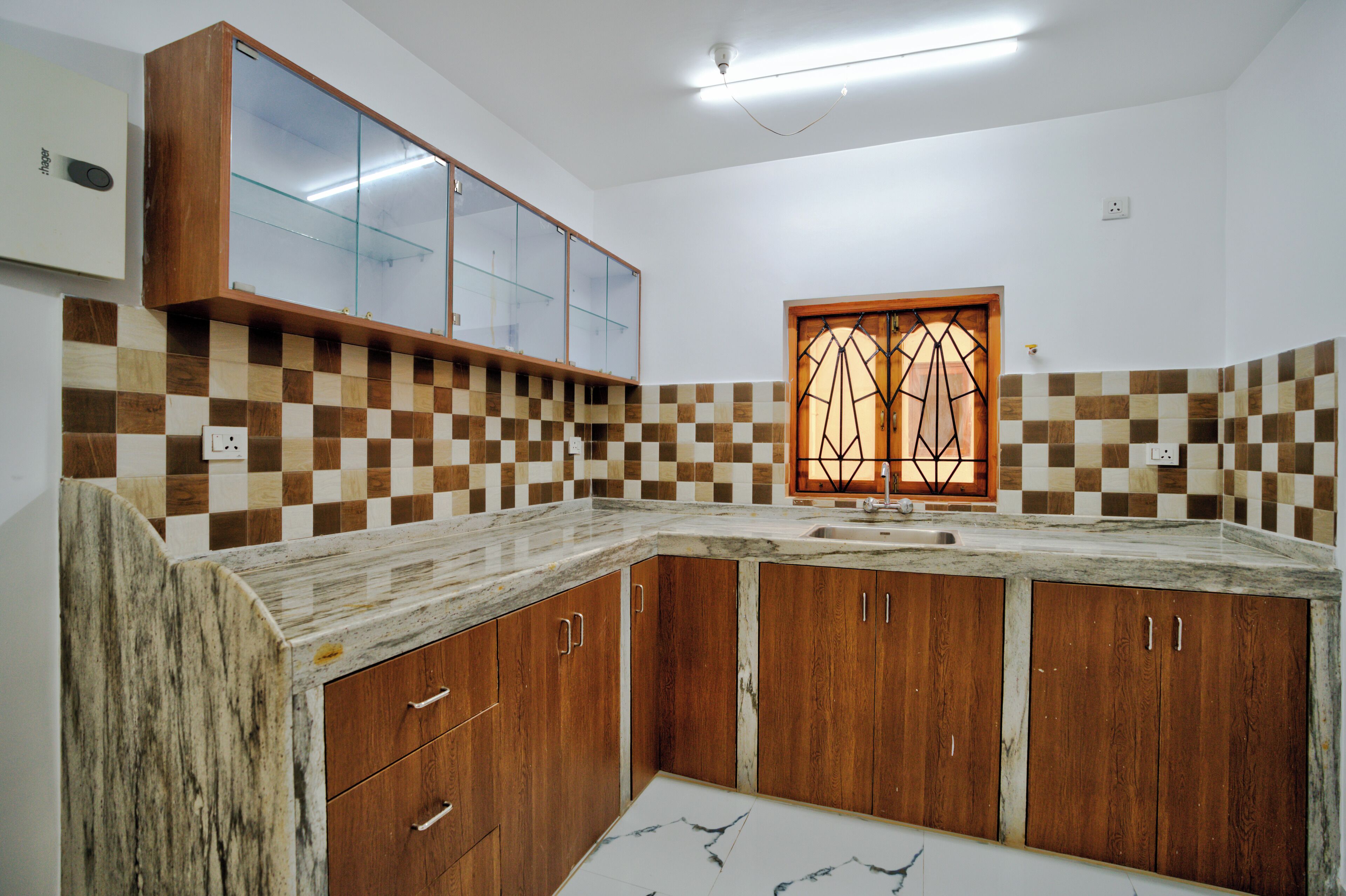 A kitchen with wooden cabinets, a marble countertop, and a checkered backsplash.
