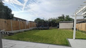 A backyard with a trampoline, a shed, and a wooden fence.