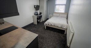A bedroom with a bed, a desk, a chair, a TV, and a window. - Cosy Studio in great location near the City (Birmingham)