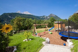 A playground with swings and a slide, surrounded by a grassy area with a mountain backdrop. - Jenner Vacation Apartment for 2 to 4 people, 52 m², 2 bedrooms, balcony (Schönau am Königssee)