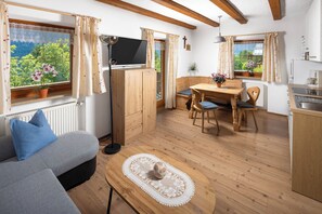Ein gemütliches Zimmer mit einer Couch, einem Holztisch und einem Fernseher.