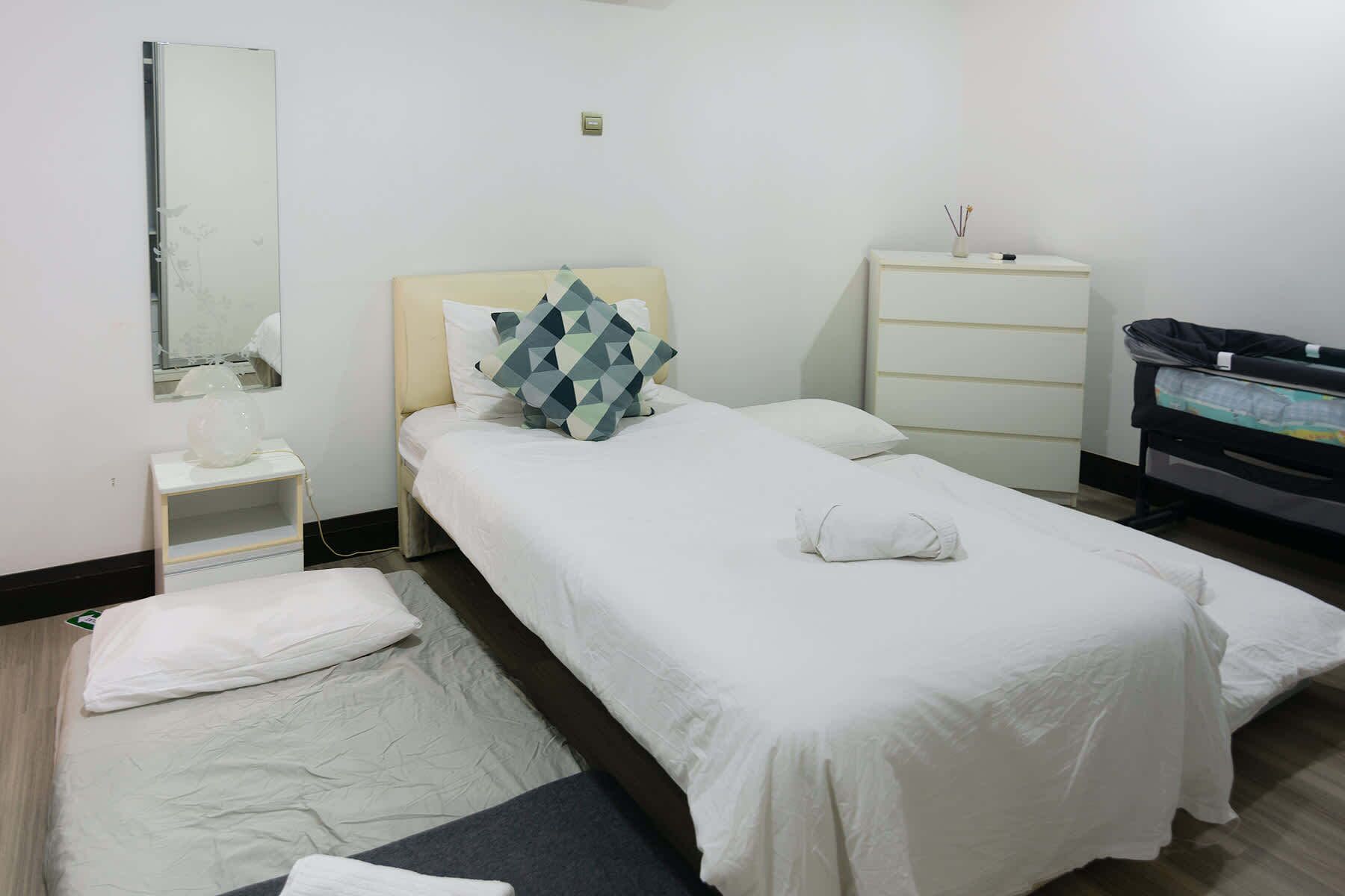 A hotel room with a bed, a bedside table, a dresser, and a mirror.