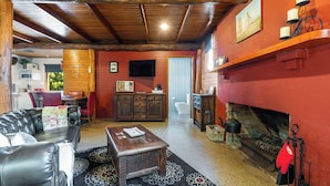 A cozy living room with a fireplace, a television, and a dining area with red chairs.
