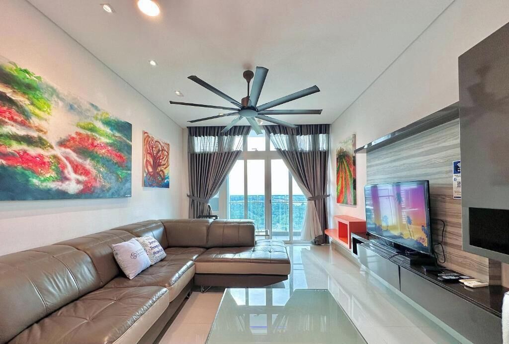 A modern living room with a sectional sofa, a flat-screen TV, and a ceiling fan.