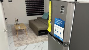 Un espace de vie compact comprenant une cuisine moderne, un canapé, une petite table basse et un réfrigérateur.