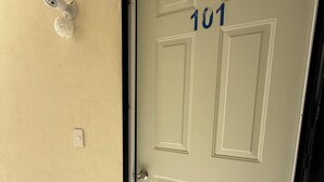Une porte blanche portant le numéro 101, un carillon et un interphone fixé au mur.