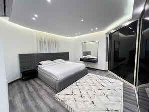 Ein modernes Schlafzimmer mit Bett, Nachttischen, einem Spiegel und einem gemusterten Teppich.
