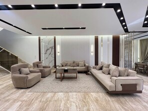A modern living room with a sofa set, coffee table, and a staircase.
