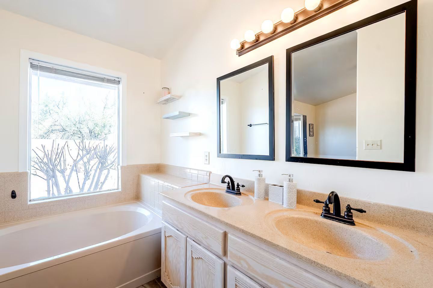 Une salle de bain moderne dotée d’une grande baignoire, de deux lavabos et d’une coiffeuse avec un miroir.