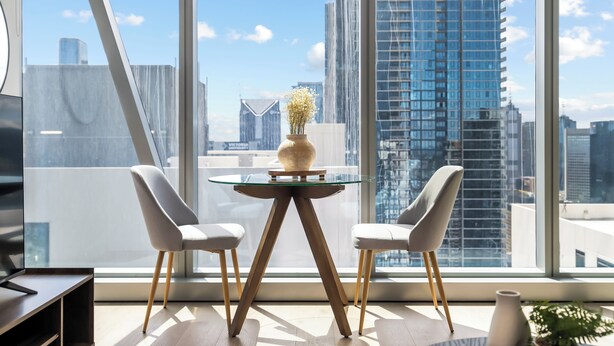 A modern room with a glass table, two white chairs, and a vase with flowers. - Designer City Retreat Heated Pool, Sauna, Steam, Gym (Melbourne)