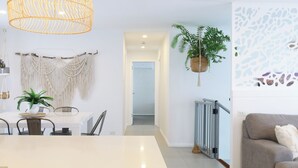 A modern living room with a white dining table, a grey sofa, and a hanging plant. - CASA DEL MAYA - 2-Bed Home By the Sea | Water Views | Air Con | Wifi | Sauna (Anna Bay)