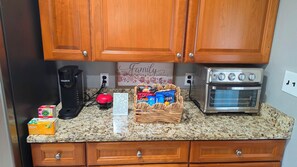 Una cocina con armarios de madera, cafetera, horno tostador y un cesto de aperitivos.