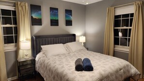 A neatly made bed with a headboard, a bedside table with a lamp, and three framed pictures on the wall. - Spacious 5-bedroom house in charming Parkville with Hot tub 24/7 (Parkville)