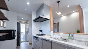 A modern kitchen with stainless steel appliances, a built-in oven, and a large window. - GUEL PALACIO (Miyakojima)