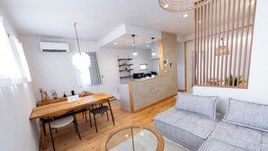A modern living room with a wooden dining table, a glass coffee table, and a grey sofa. - GUEL PALACIO (Miyakojima)