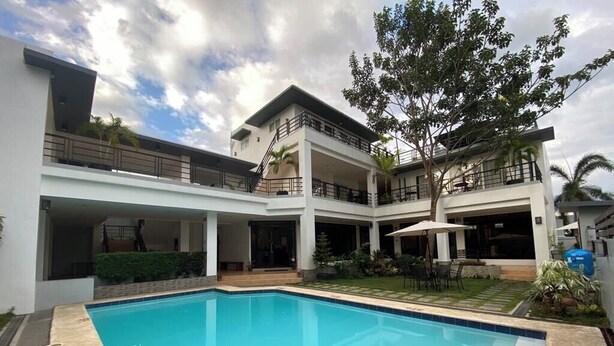 A modern building with a swimming pool, multiple balconies, and a garden area.