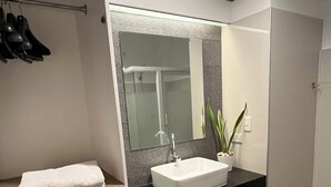 A modern bathroom with a white vanity, a large mirror, and a black countertop.