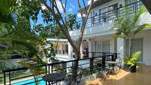 A poolside area with a tiled floor, metal tables and chairs, and a view of a swimming pool.