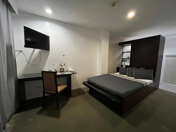 A modern hotel room with a bed, a desk, and a flat-screen TV mounted on the wall. - Be-ing Suites Davao (Davao)