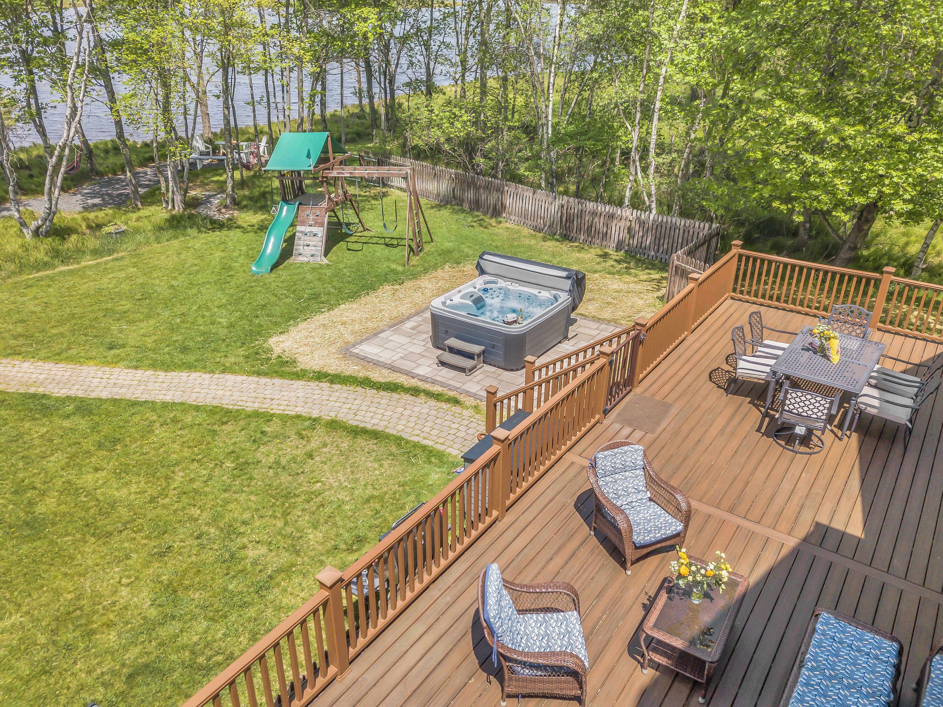 Eine Terrasse mit Gartenmöbeln, einem Whirlpool und einer Rutsche.