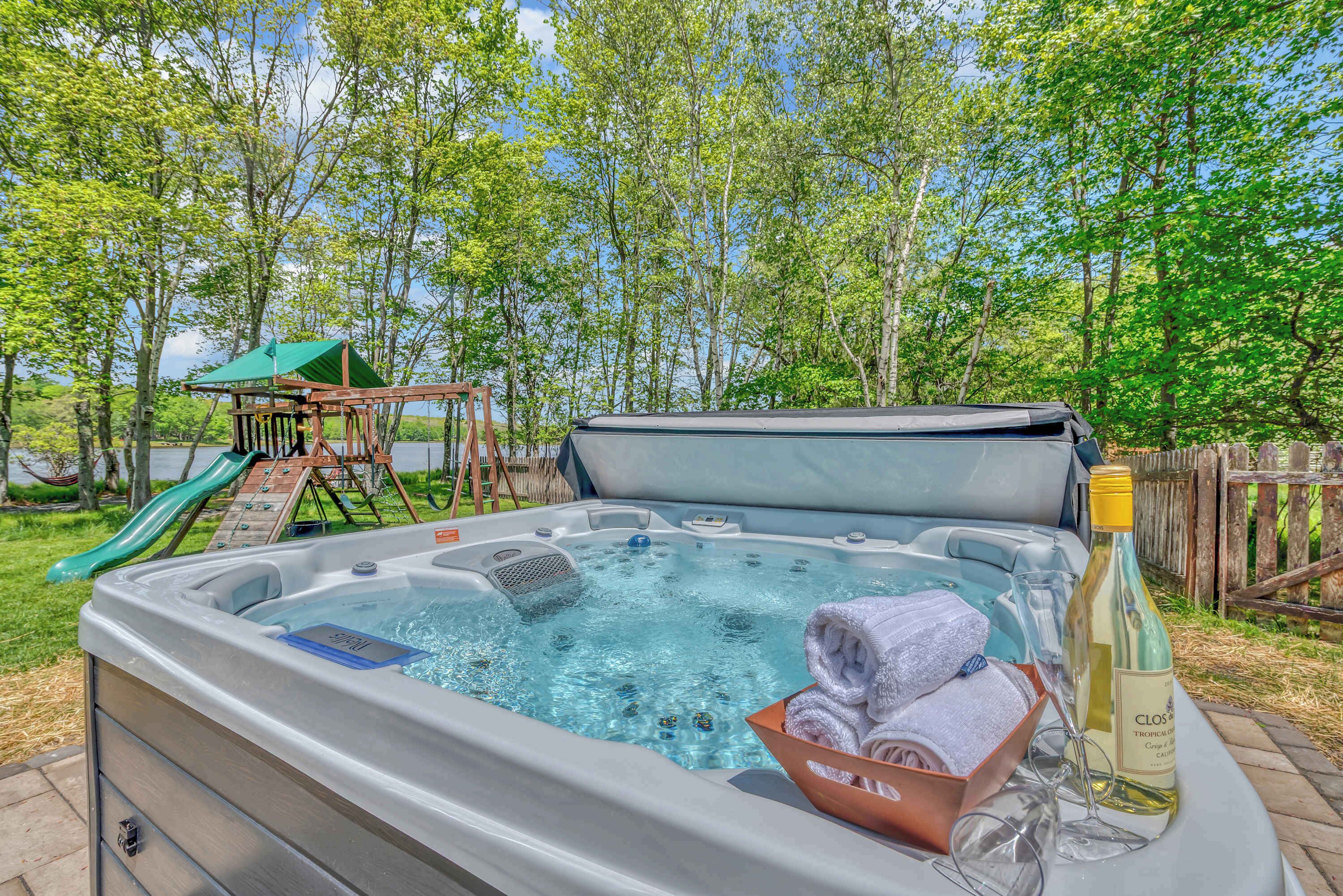 Een jacuzzi met glijbaan, handdoeken en een fles wijn.