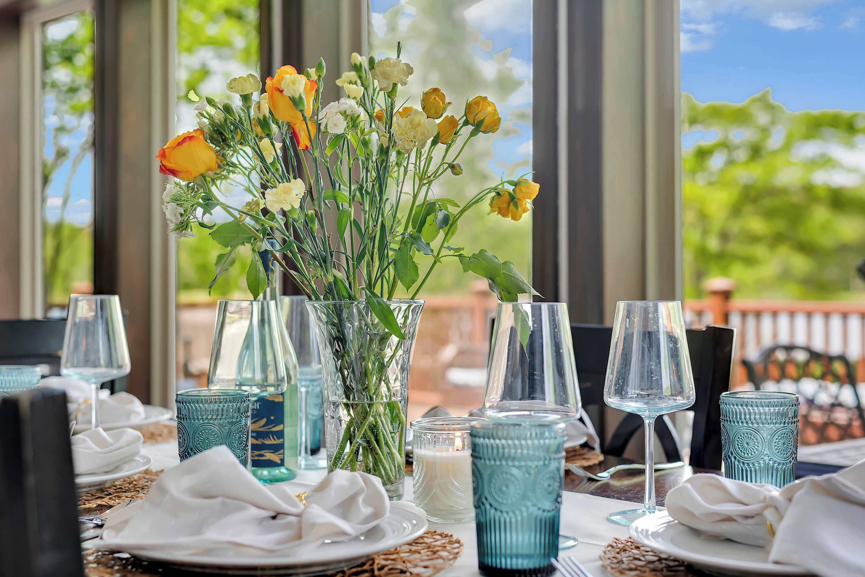 Une table dressée pour le dîner, avec un vase de fleurs, de la belle verrerie et une bougie.