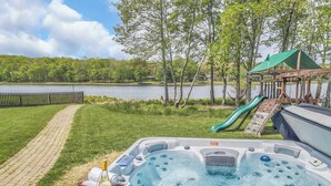 A hot tub with a bottle of wine, a slide, and a view of a lake. - Lakefront Home in the Poconos with Hot Tub! (Albrightsville)