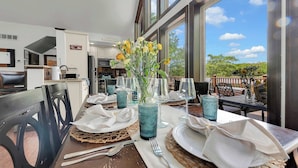 A dining table set with blue glassware, white napkins, and a vase with yellow flowers. - Lakefront Home in the Poconos with Hot Tub! (Albrightsville)