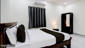 A hotel room with a bed, a nightstand, a wardrobe, and an air conditioning unit.