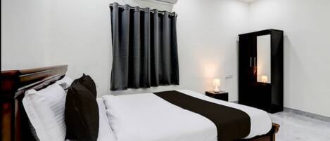 Une chambre d’hôtel équipée d’un lit, d’une table de chevet, d’une armoire et d’un appareil de climatisation.