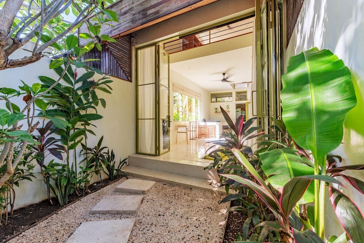 Una casa con un patio cubierto, un comedor y una cocina visible a través de la puerta abierta.