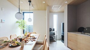 A modern dining area with a wooden table set for a meal, a kitchen with appliances, and a large window providing natural light. - 2025/10Open! Lux Villa(132 m2) 6 min Shibuya/4m Ebisu (Ebisu, Shibuya-ku,)